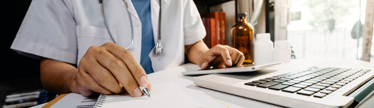 Dokter zit achter zijn bureau en werkt zijn administratie bij.
