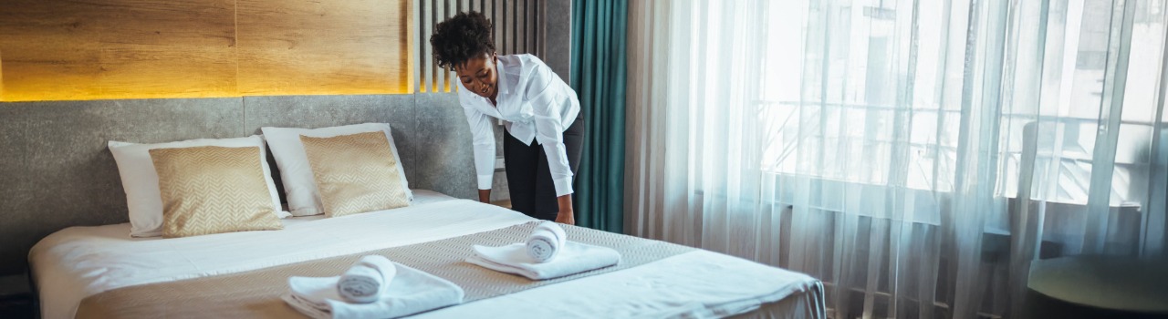 Schoonmaker maakt een bed op in een hotelkamer.